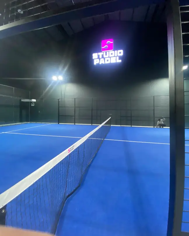 A court under the lit Studio Padel sign
